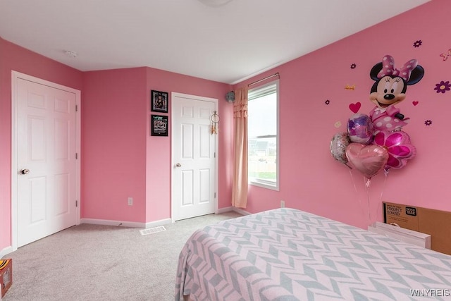 bedroom featuring visible vents, light colored carpet, and baseboards