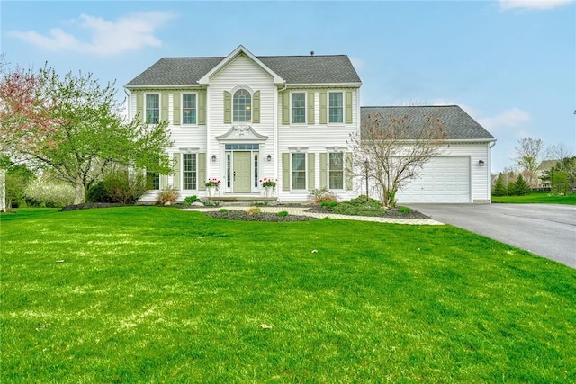 colonial home featuring a garage, driveway, and a front yard