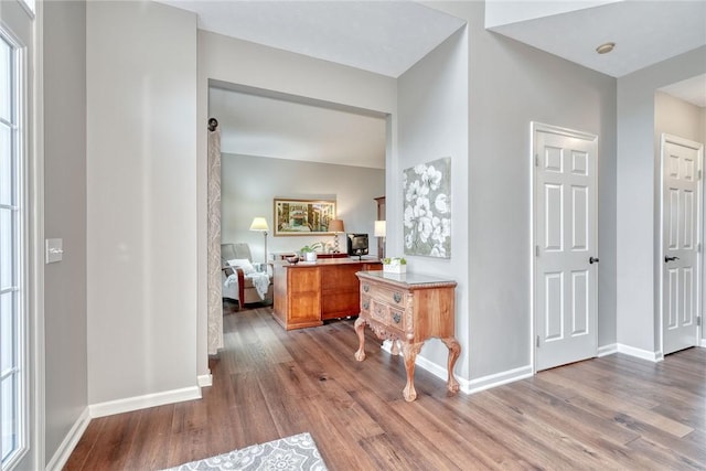hallway featuring wood finished floors and baseboards