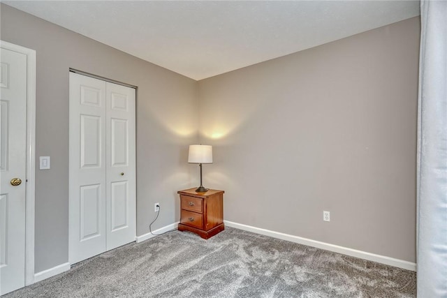 unfurnished bedroom with a closet, carpet floors, and baseboards