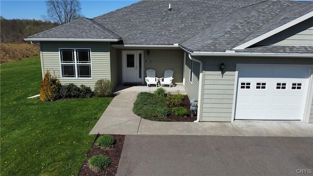 view of front of home with a garage, a front yard, and roof with shingles