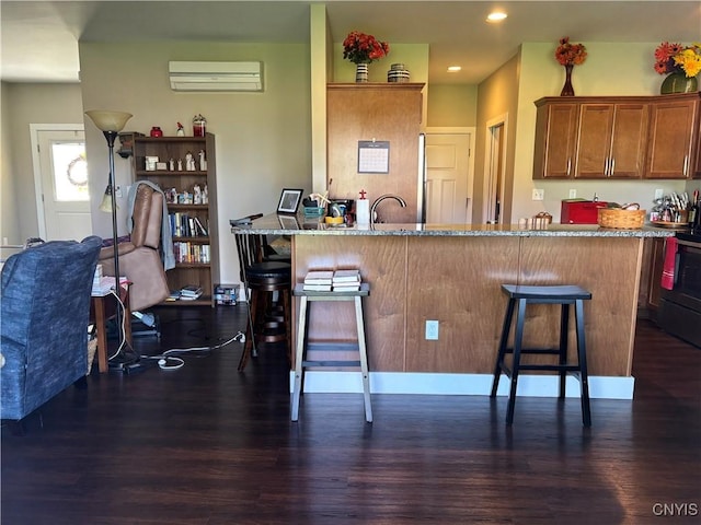 kitchen featuring dark wood-style floors, a kitchen bar, brown cabinets, and a wall mounted AC