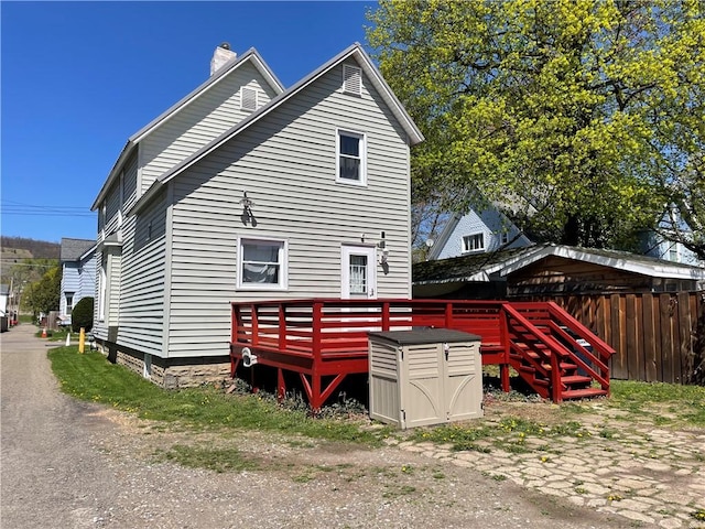 back of property featuring fence, a chimney, and a wooden deck