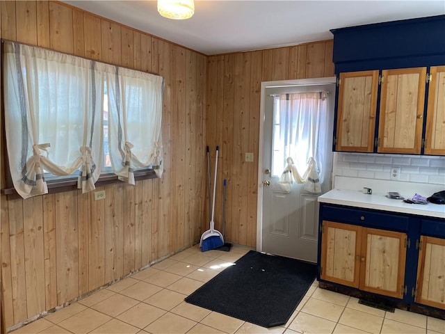 kitchen with wood walls, light tile patterned flooring, and light countertops