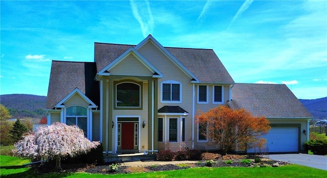 view of front facade with a mountain view, driveway, a shingled roof, and an attached garage