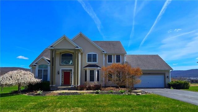 traditional-style home featuring a front yard, a garage, and aphalt driveway
