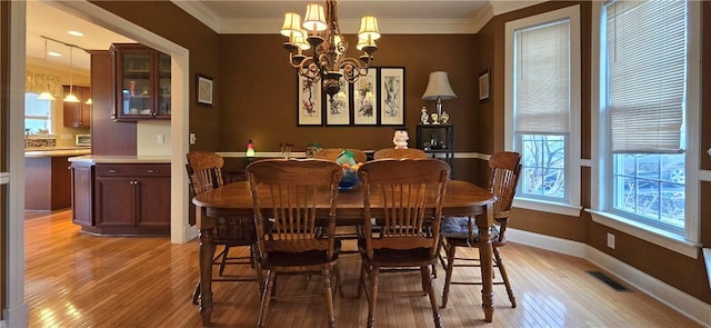 dining room with ornamental molding, visible vents, light wood finished floors, and a notable chandelier