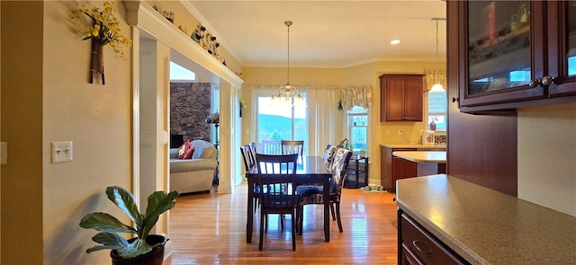 dining room featuring crown molding, a healthy amount of sunlight, a chandelier, and light wood-type flooring