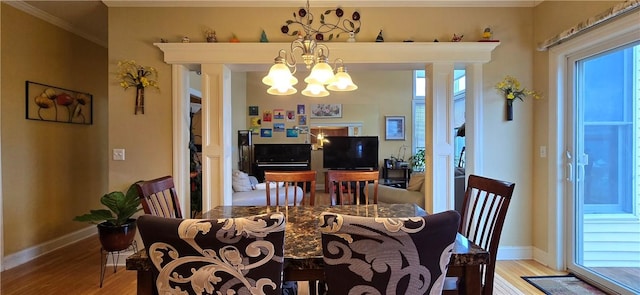 dining space with a chandelier, baseboards, crown molding, and light wood finished floors