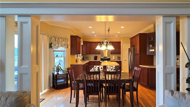 dining area featuring crown molding, light wood finished floors, a chandelier, and a toaster