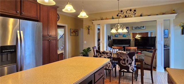 kitchen with an inviting chandelier, stainless steel refrigerator with ice dispenser, wood finished floors, and light countertops