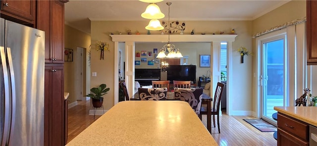 dining space with baseboards, a notable chandelier, crown molding, and light wood-style flooring