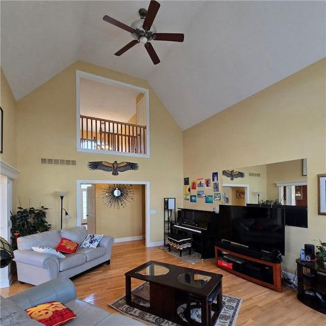 living area with a ceiling fan, high vaulted ceiling, wood finished floors, and visible vents