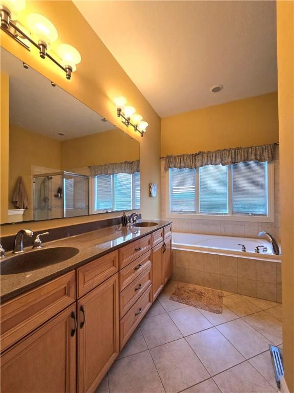 full bath with a shower stall, a bath, tile patterned flooring, and a sink