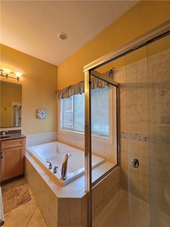 full bathroom with tile patterned floors, a stall shower, a garden tub, and vanity