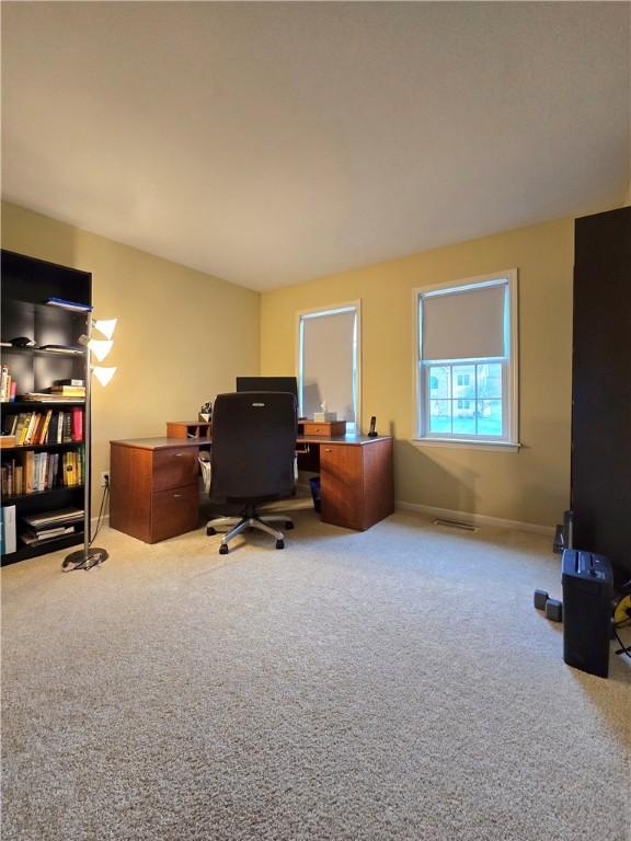 carpeted office space featuring baseboards and visible vents