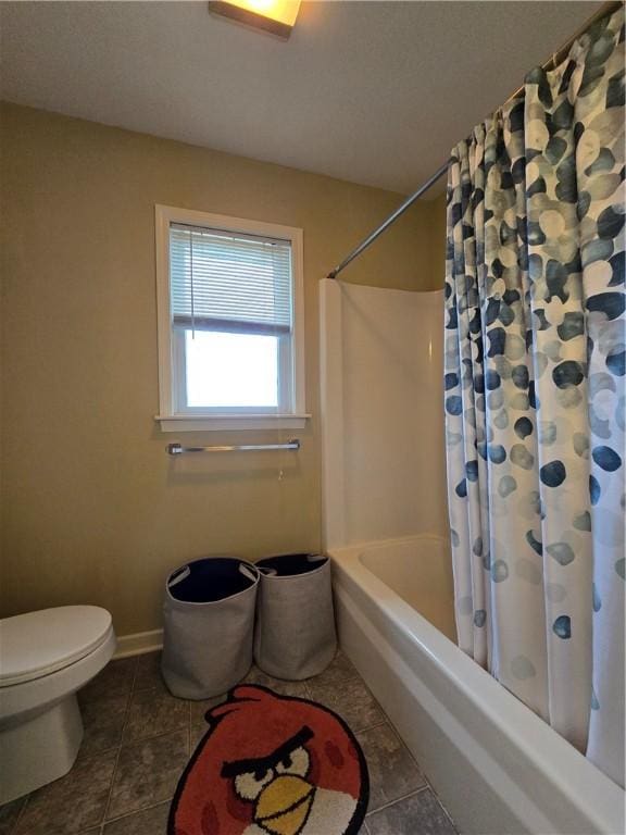 full bath featuring tile patterned floors, shower / bath combo, toilet, and baseboards
