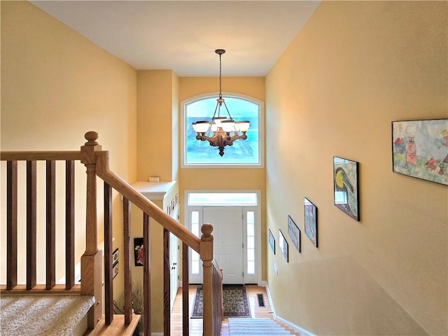 entryway with stairs, baseboards, visible vents, a notable chandelier, and a towering ceiling
