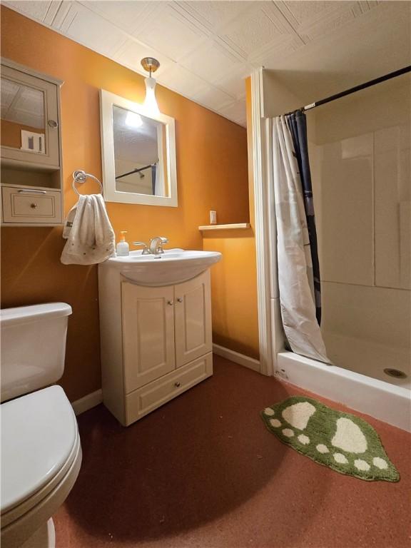 bathroom with toilet, a stall shower, and baseboards