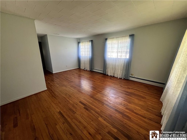 empty room with wood-type flooring, baseboards, and a baseboard radiator
