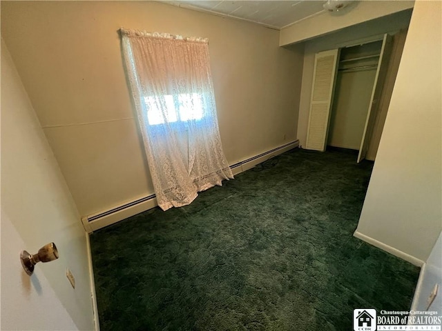 unfurnished bedroom featuring dark carpet, a closet, and baseboard heating