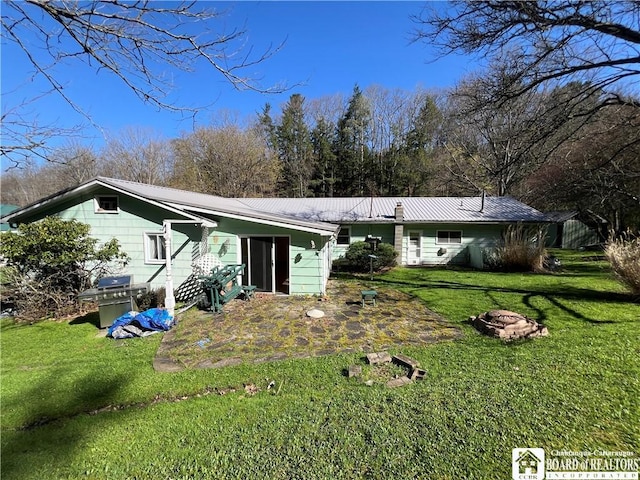 rear view of house featuring a lawn, metal roof, and an outdoor fire pit