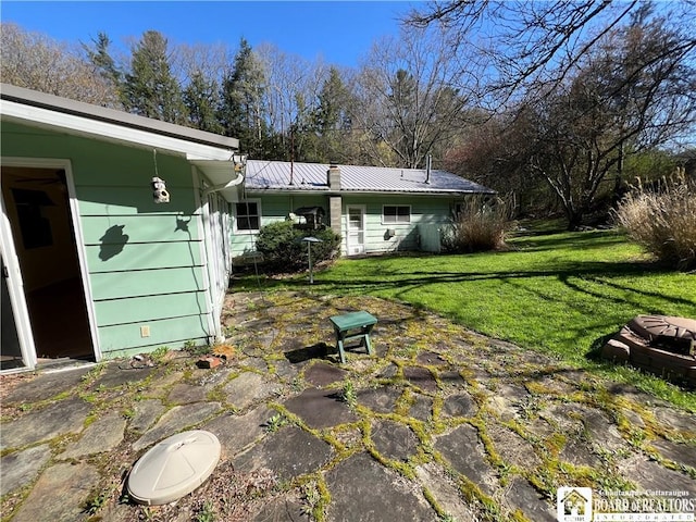 back of house with metal roof and a lawn