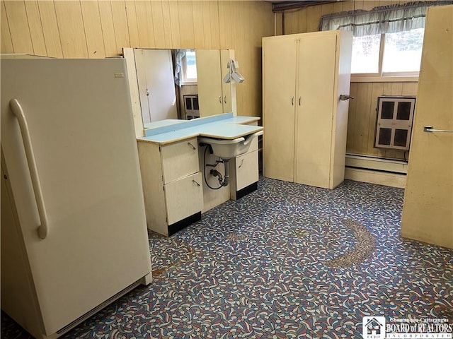 kitchen with wood walls, carpet, light countertops, baseboard heating, and freestanding refrigerator