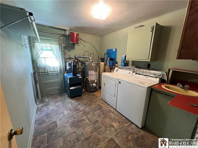 laundry room featuring gas water heater, a sink, cabinet space, washing machine and clothes dryer, and stone finish flooring