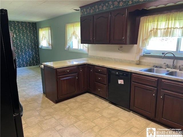 kitchen with wallpapered walls, light countertops, black appliances, a sink, and a peninsula