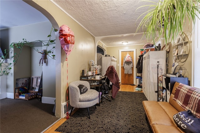 interior space with a textured ceiling, ornamental molding, and arched walkways