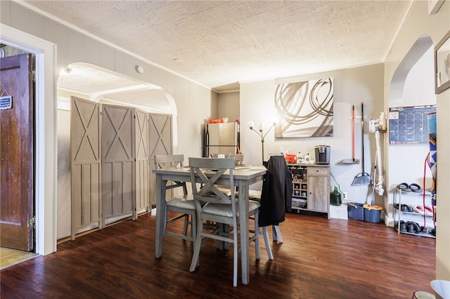 dining room with arched walkways, wood finished floors, and ornamental molding