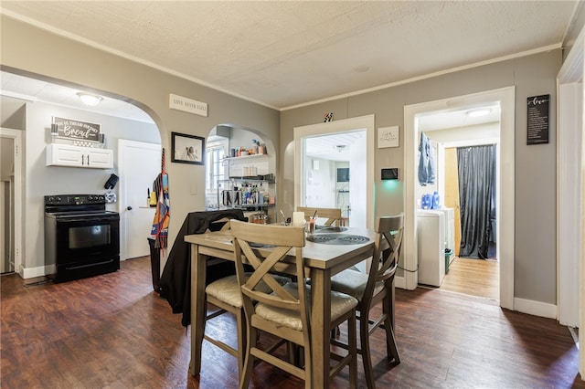 dining space featuring ornamental molding, arched walkways, dark wood-style flooring, and washer / dryer