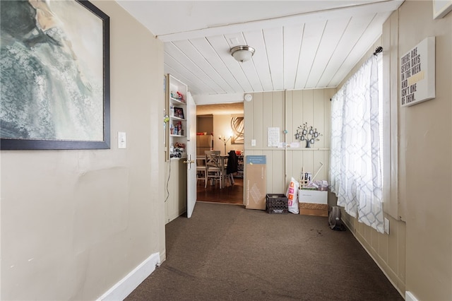 hallway featuring carpet flooring and baseboards