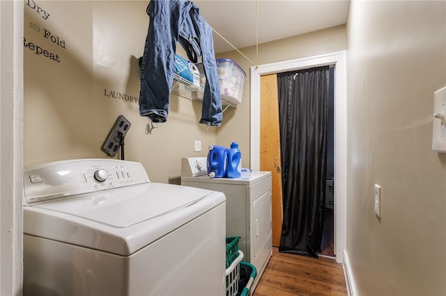 laundry area featuring wood finished floors, laundry area, and washing machine and dryer