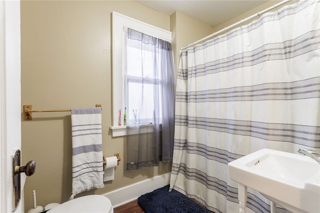 full bathroom with baseboards, wood finished floors, a shower with curtain, and a sink