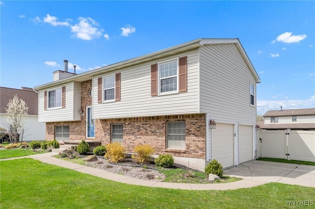 raised ranch featuring a front lawn, a garage, brick siding, driveway, and a chimney