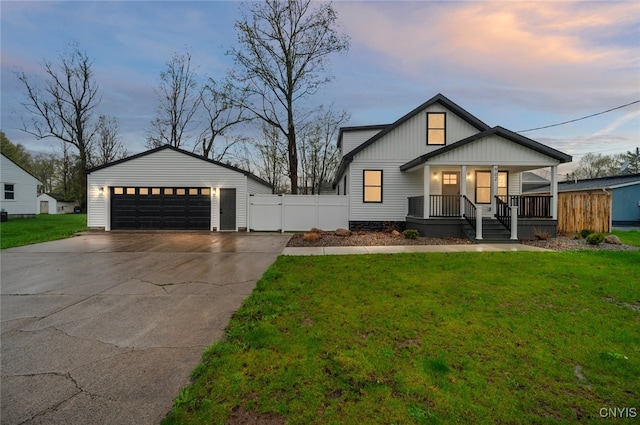 view of front of home featuring covered porch, a detached garage, and a yard