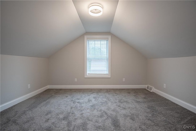 additional living space with baseboards, visible vents, carpet, and vaulted ceiling