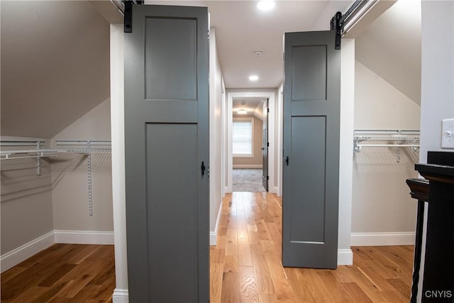 spacious closet with a barn door and light wood finished floors
