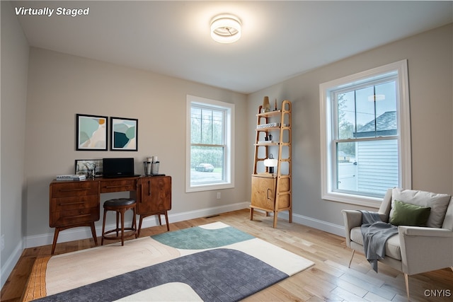 office space featuring a wealth of natural light, wood finished floors, visible vents, and baseboards