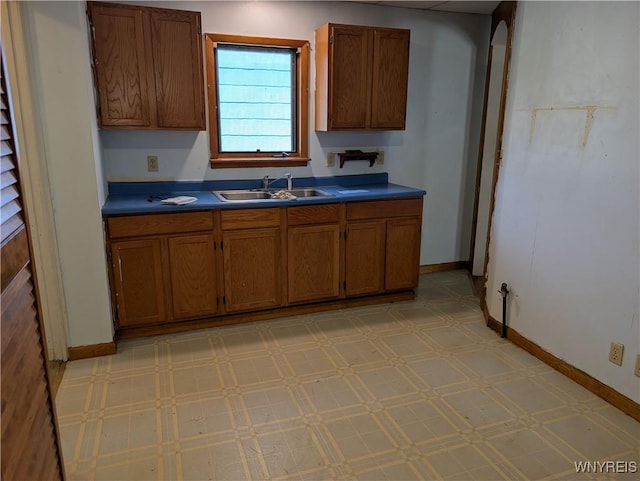 kitchen with dark countertops, a sink, brown cabinets, and light floors