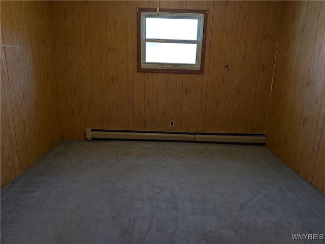 carpeted spare room featuring wood walls and a baseboard radiator