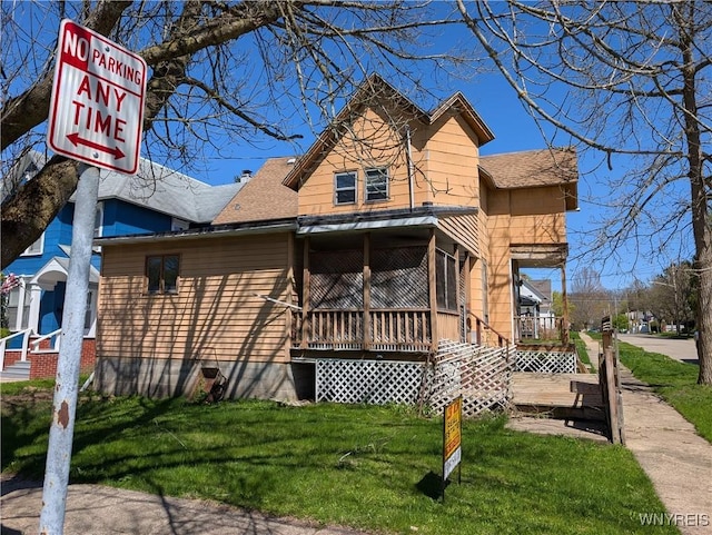 rear view of house with a yard and roof with shingles
