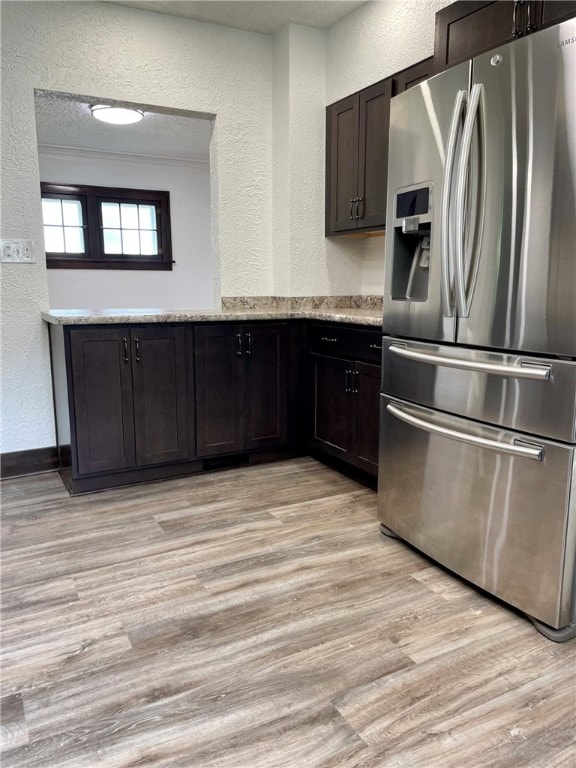 kitchen featuring a textured wall, dark brown cabinets, light wood finished floors, and stainless steel fridge with ice dispenser