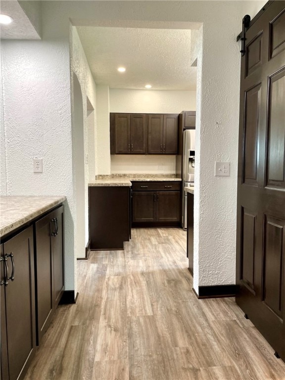 interior space with a textured wall, light wood-type flooring, recessed lighting, and baseboards