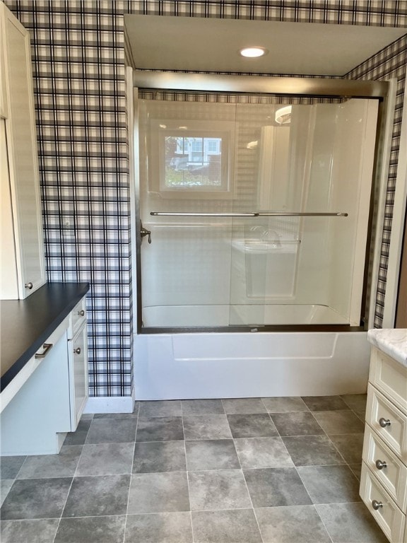 bathroom featuring stone finish floor, enclosed tub / shower combo, and vanity