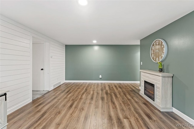 65 Guilford Ln Unit 5, Amherst, NY 14221 - unfurnished living room with recessed lighting, a glass covered fireplace, visible vents, baseboards, and wood finished floors