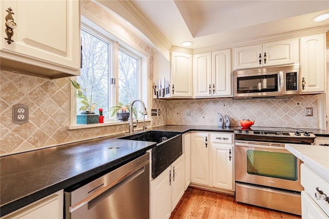 kitchen with stainless steel appliances, dark countertops, a sink, and tasteful backsplash