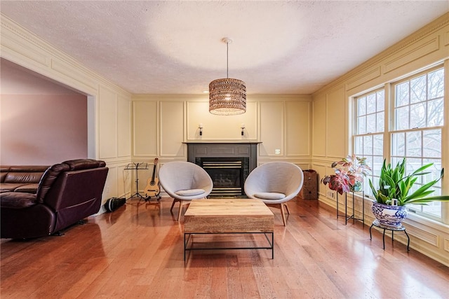 sitting room with light wood-style floors, a glass covered fireplace, and a decorative wall